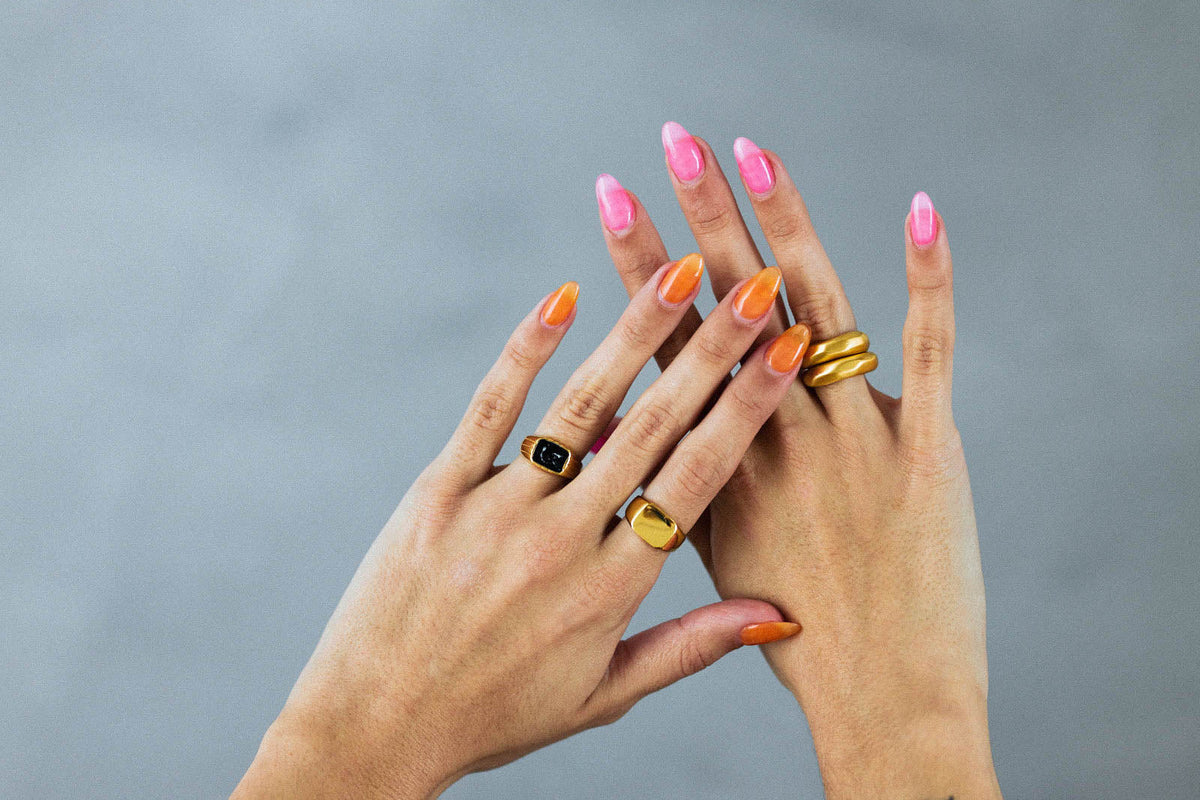 Colorful summer nail art suggestions featuring pink and orange manicures adorned with stylish rings.