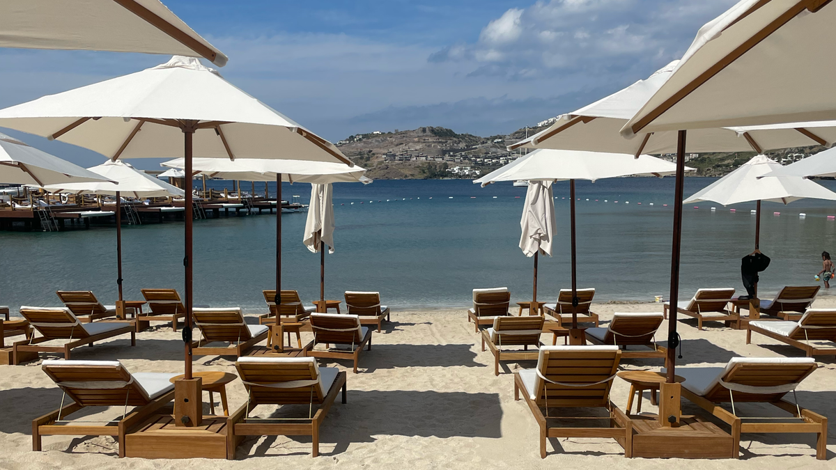 Beach lounge chairs under umbrellas with a tranquil sea view, perfect for female solo travel myths exploration.