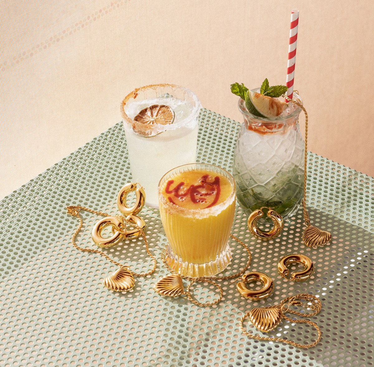 Cocktails and jewelry pairings featuring summer drinks and elegant gold jewelry on a textured surface.