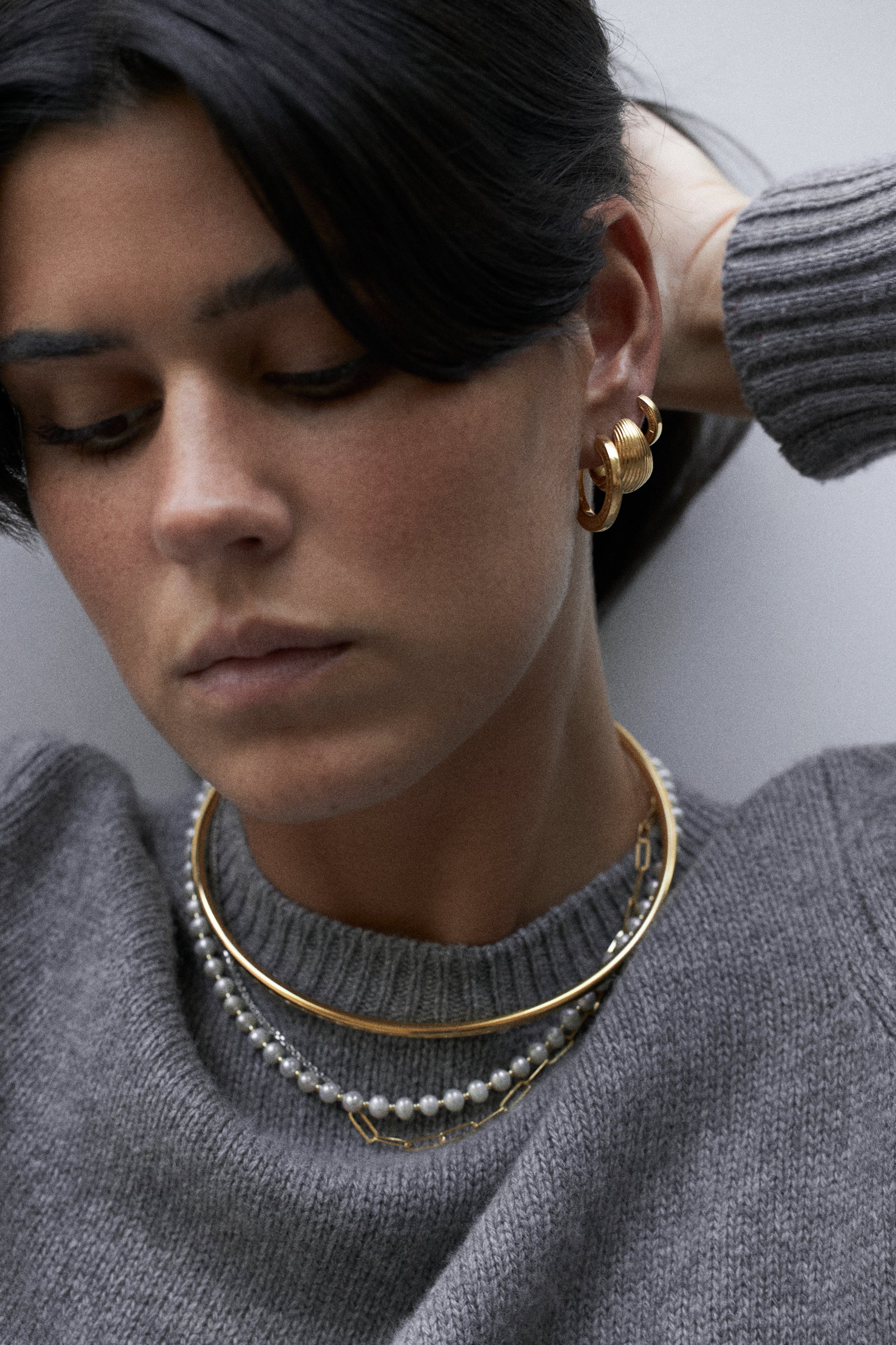 model wearing filomena necklace, little arlo choker, magdalene choker, jodie huggies, maxi tilly earrings and maxi jodie earrings in gold