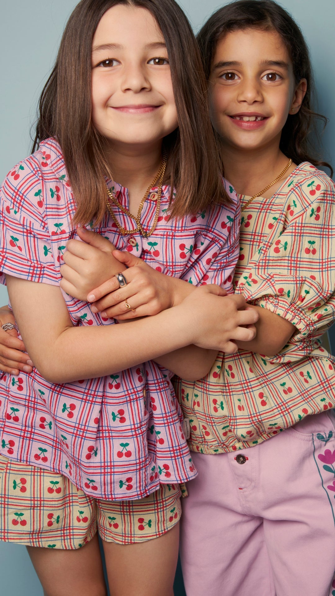 Two young girls smiling together, wearing colorful outfits and jewelry, ideal for jewelry tips for sensitive skin.