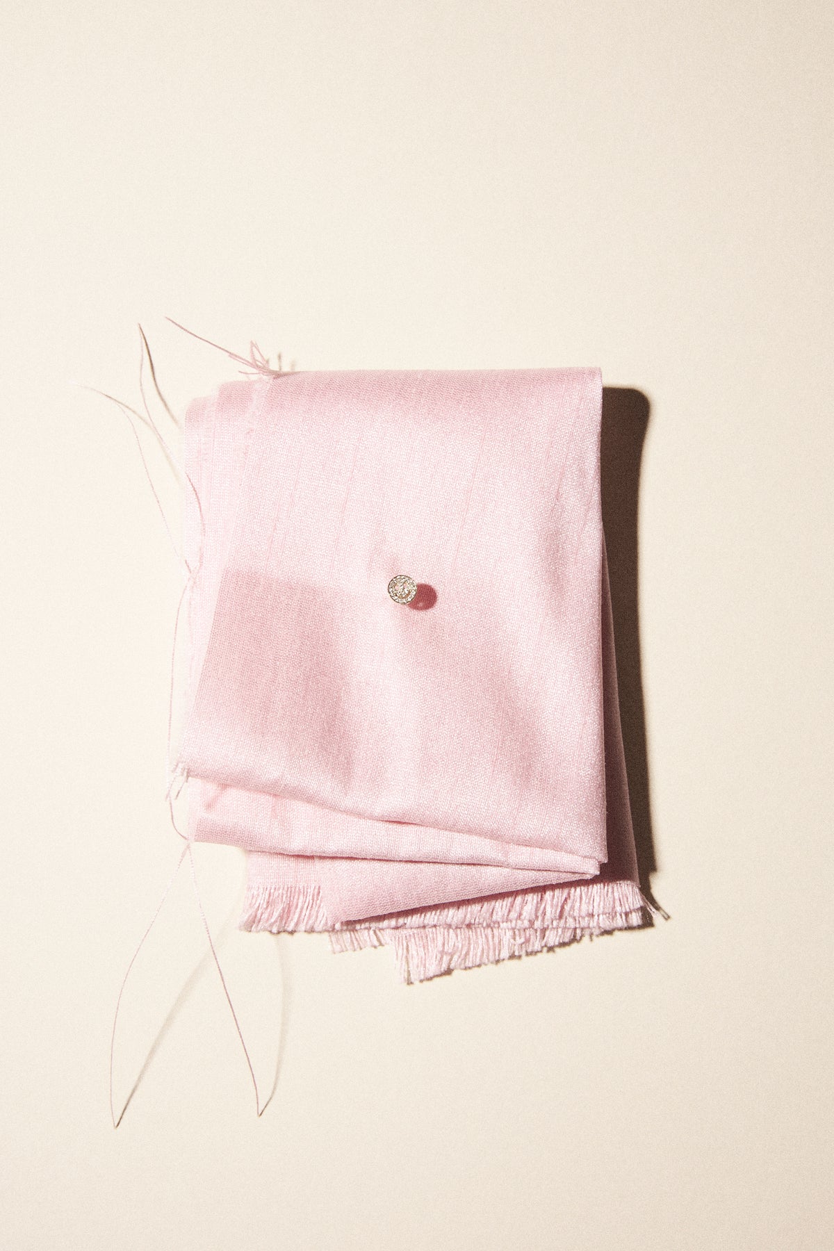 Handmade stud earrings in sterling silver and gold resting on a pink fabric backdrop.