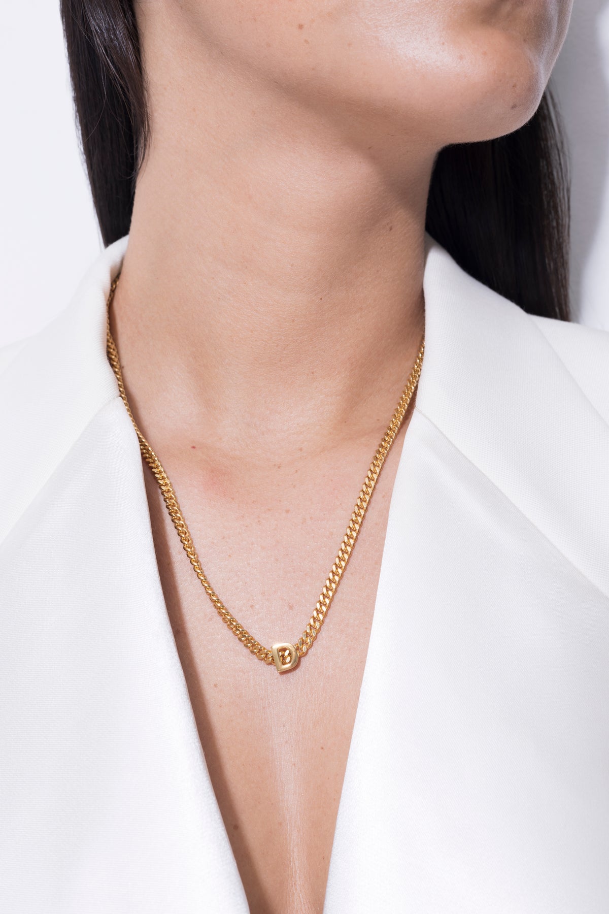 Close-up of a woman wearing a personalized initial necklace in gold, featuring the letter 'B'.
