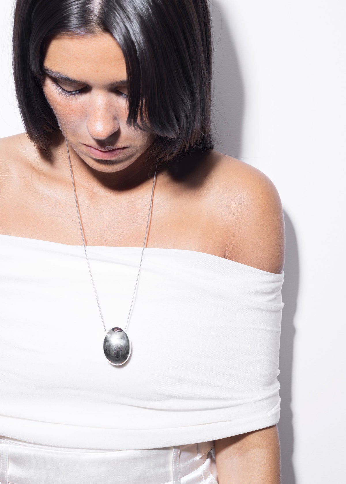 Handmade long necklaces in sterling silver worn by a model with a clean neckline.