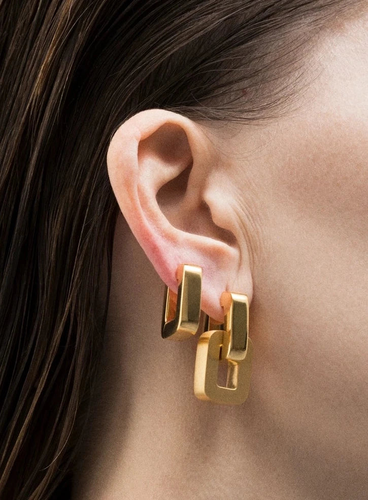 Handmade drop earrings in sterling silver showcased on an ear, featuring a modern design in gold.