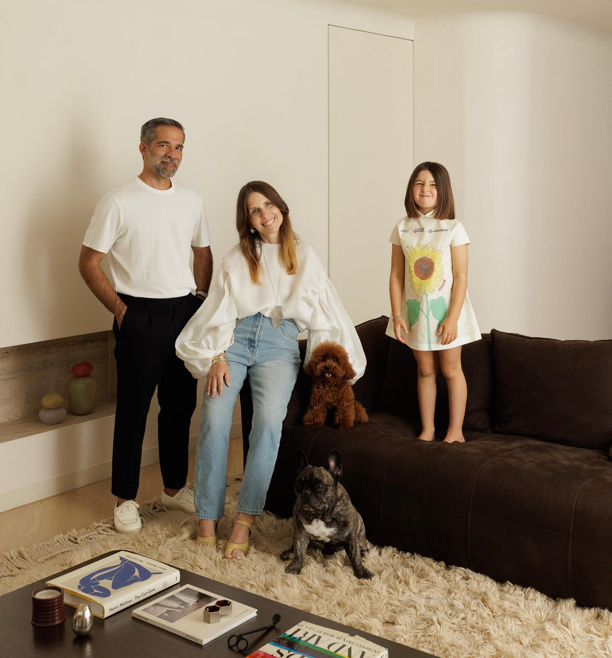 Família de três pessoas com dois cães numa sala de estar