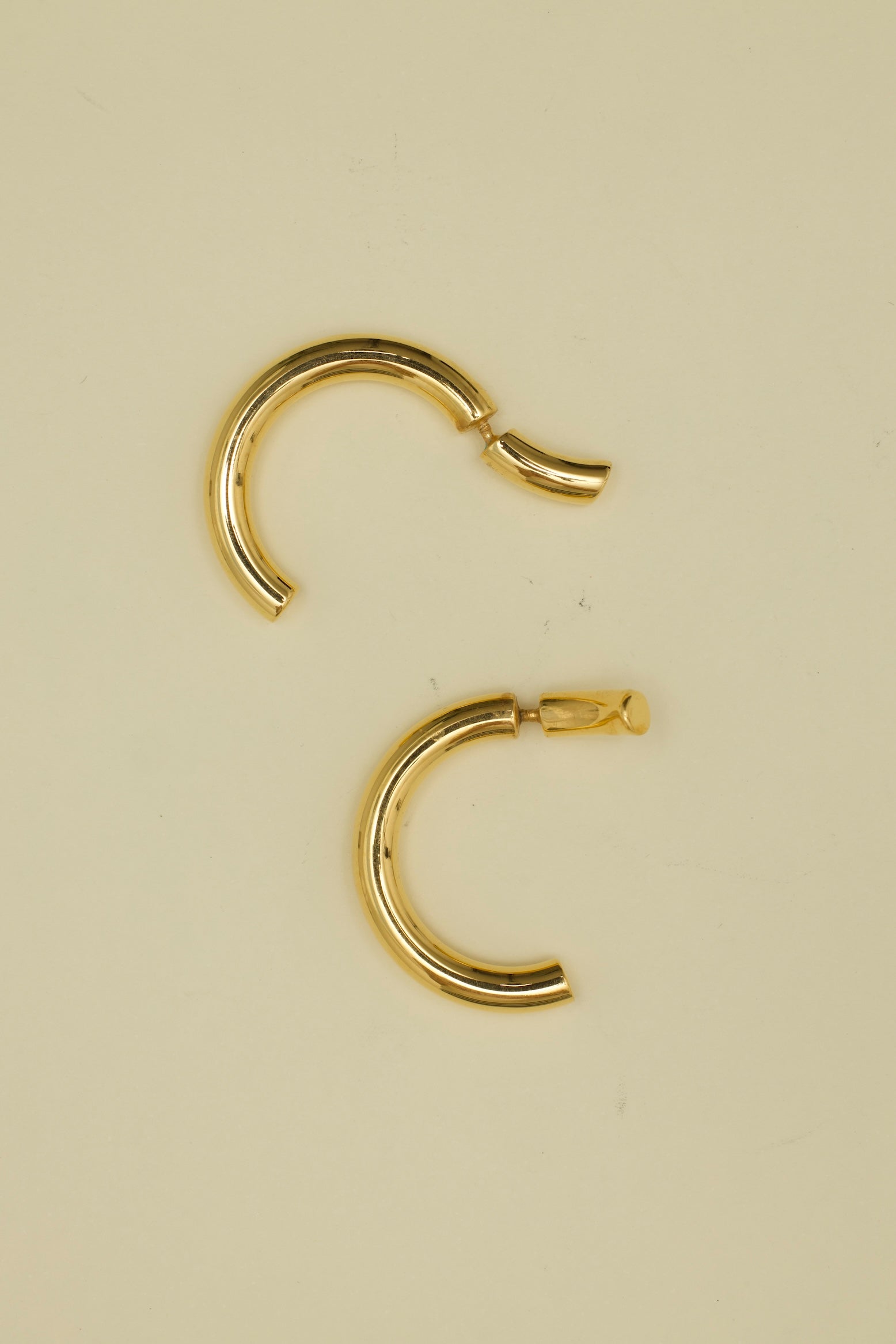 Gold hoop earrings on a beige background