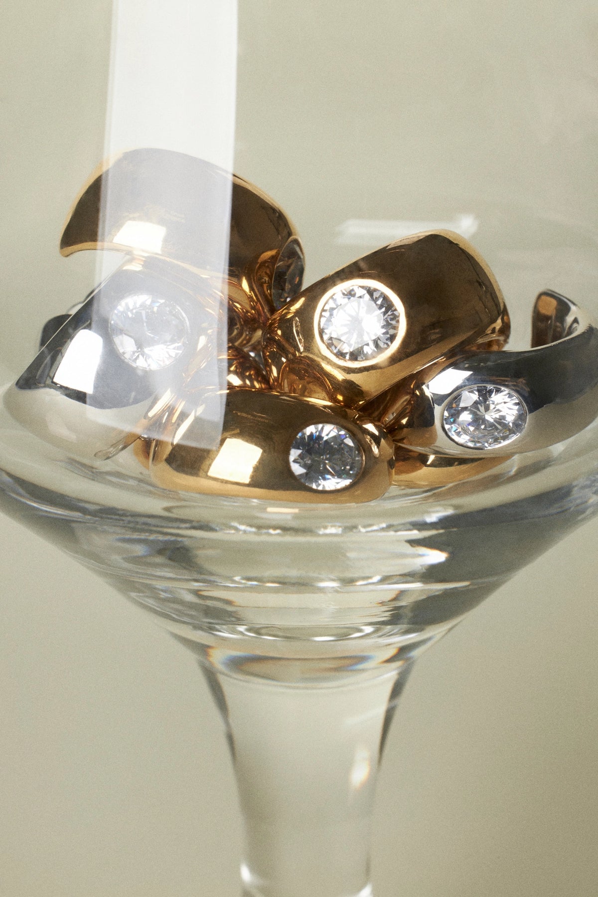 CINCO statement rings set in a glass showcasing gold and silver finishes with sparkling stones.