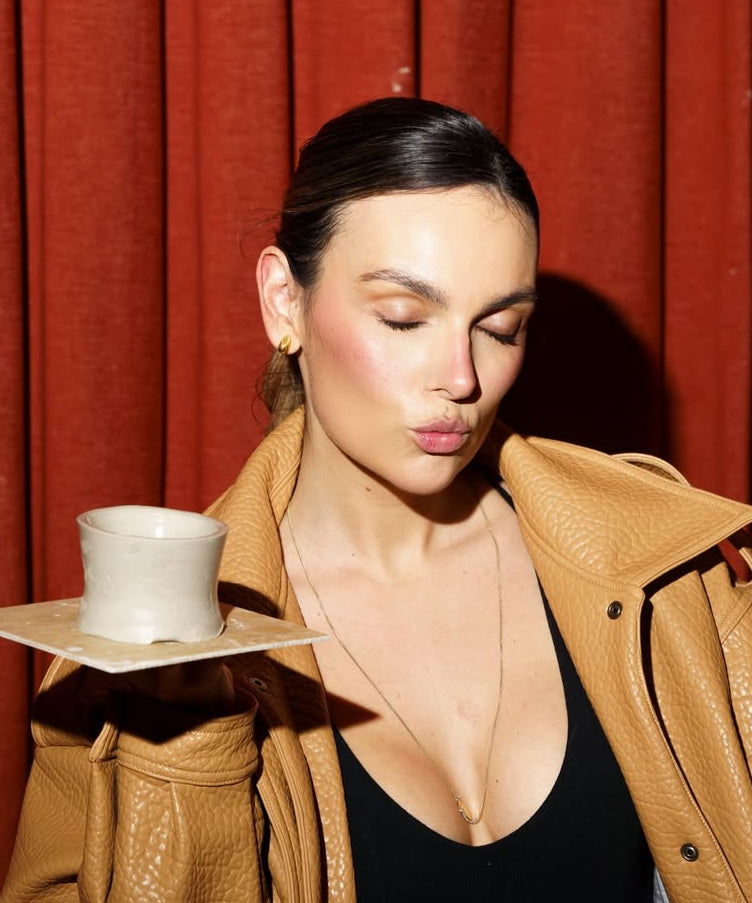 Mafalda Castro holding a white cup against a red curtain background wiht constantin mini earrings from cinco